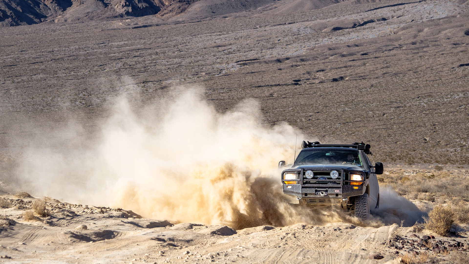 black Ford kicking up dust driving in the desert
